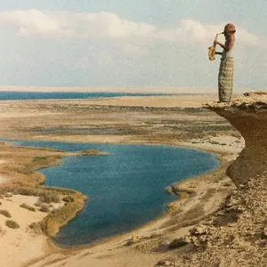 Album cover of Malik: a saxophonist standing on a desert cliff above a blue pool