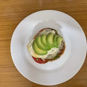 Avocado, egg and tomato on a biscuit, plated on a white plate