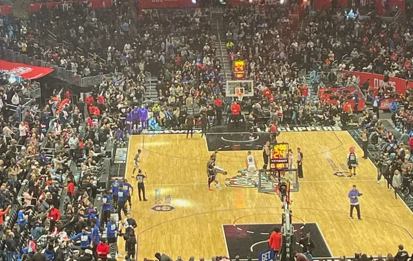 Basketball game seen from the upper seats of an arena, with the court below and a player on the big screen above